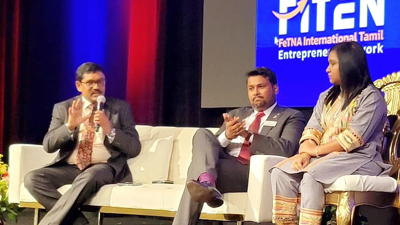 Three panellists seated on stage at the FiTEN Global Tamil Entrepreneurs Summit, one speaking into a microphone.