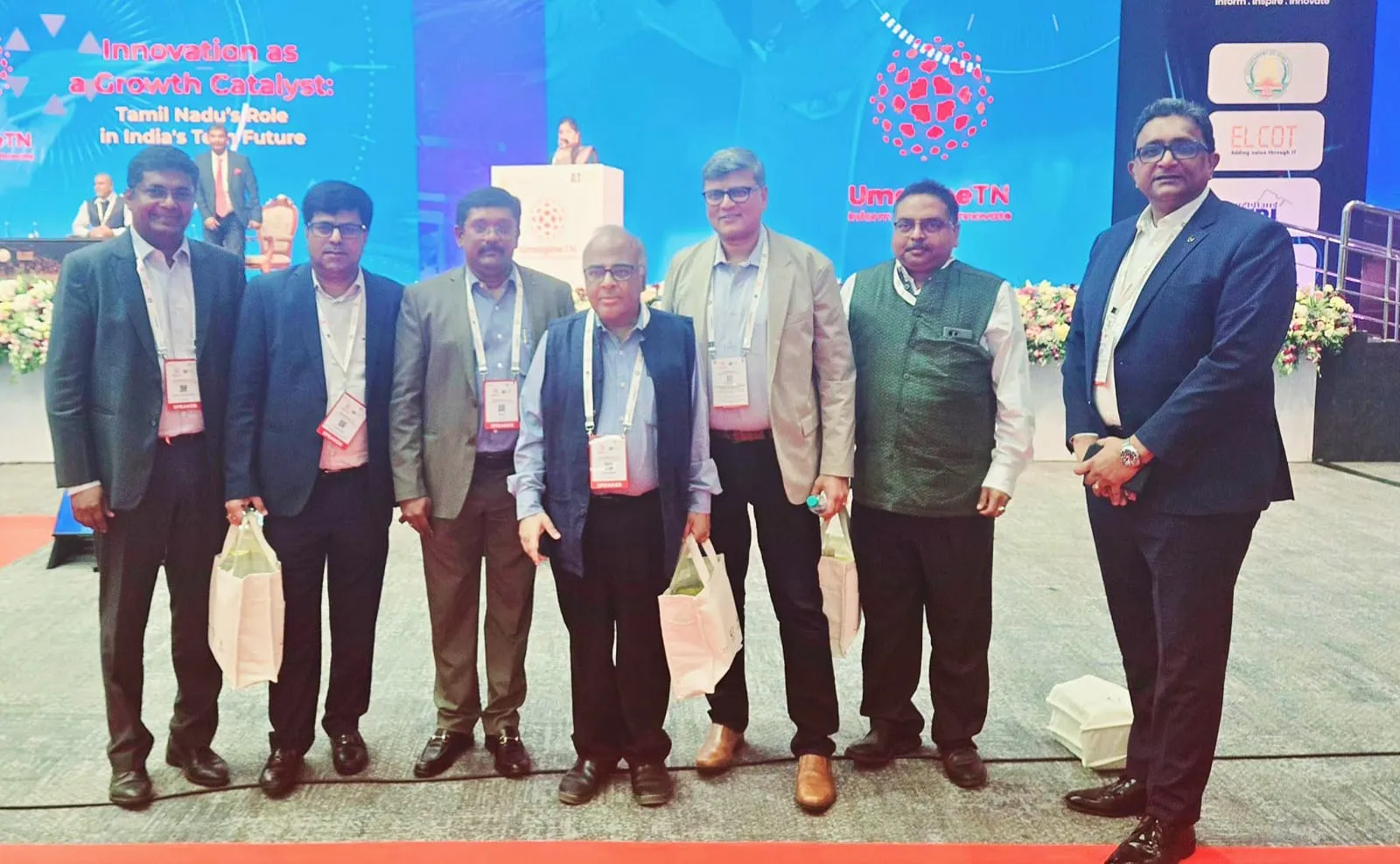 Speakers photographed together at UmagineTN, beside a screen reading 'Innovation as a Growth Catalyst: Tamil Nadu's Role in India's Tech Future'.